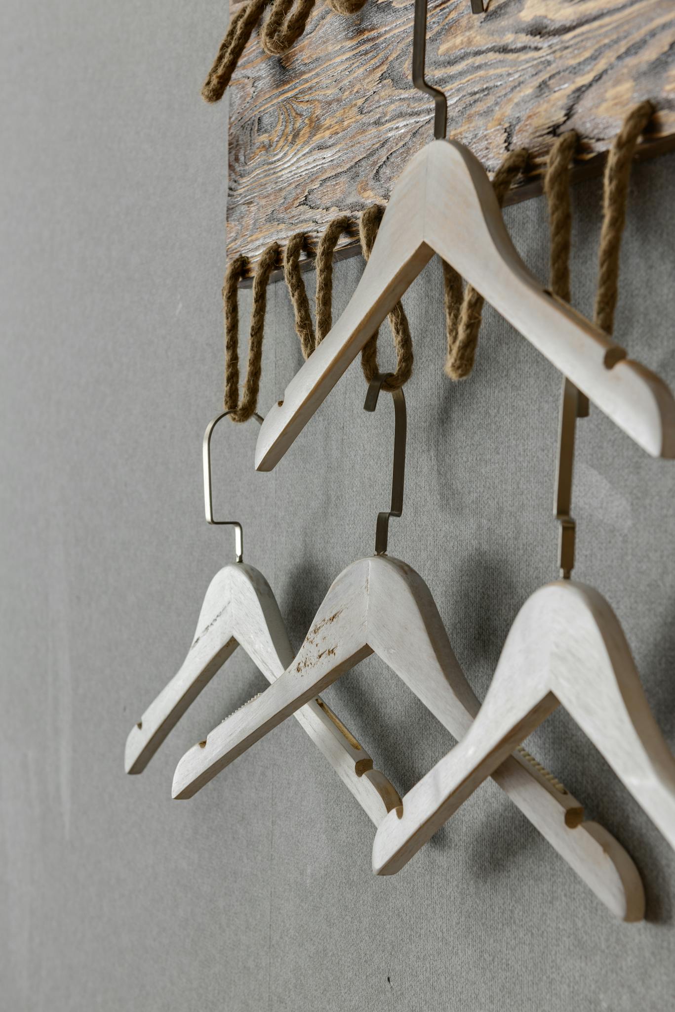 A minimalist arrangement of wooden hangers hanging from rustic rope on a wall.